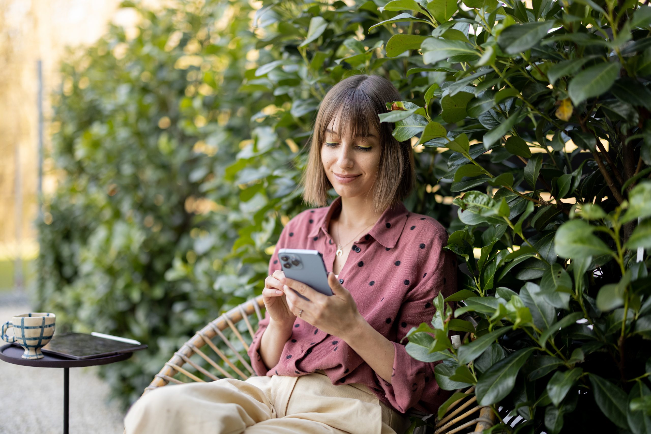 Happy woman with smart phone on natural background outdoors